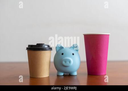 Tazza di caffè artigianale levitating con biggy bank su sfondo blu. Foto Stock