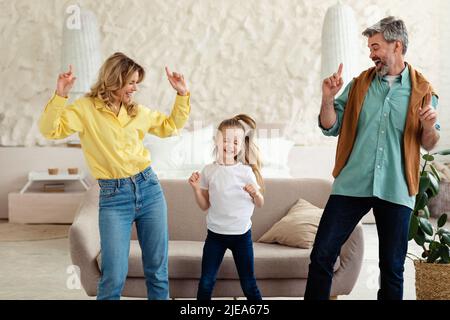 Genitori allegri e bambina che ballano divertirsi a casa Foto Stock