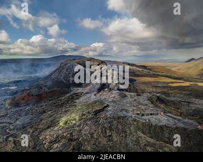 Paesaggio con crateri attivi sulla penisola islandese di Reykjanes. Flusso di lava raffreddato intorno al cratere con colonne a vapore individuali. Giornata di sole con cl Foto Stock