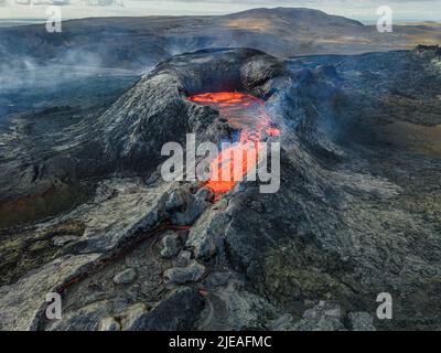 Ammira il cratere di un vulcano attivo con un forte flusso di lava all'inizio di un'eruzione. Paesaggio sulla penisola di Reykjanes dell'Islanda. Scuro Foto Stock