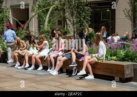 Giovani donne o adolescenti seduti su una panchina al Rockefeller Center plaza a New York City, Stati Uniti d'America Foto Stock