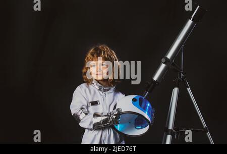 Piccolo bambino vuole volare uno nello spazio, ragazzo con telescopio che indossa un casco astronauta. Spazio di copia. Successo, creatività e concetto di start up. Foto Stock