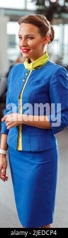 Gioioso assistente di volo donna in piedi nel terminal dell'aeroporto Foto Stock