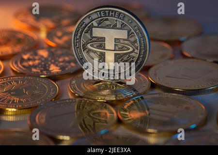 Laccio USDT Cryptocurrency Physical Coin posto su cripto altcoins e illuminato con luci arancioni e blu nel Backgrone scuro. Scatto macro. Foto Stock