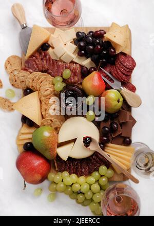 Piatto di formaggi. Fette di formaggio su piatti, uva, mele, pere, pane, salsiccia, salame, olive, olive nere, biscotti, spuntini, cracker, vino. Superiore Foto Stock