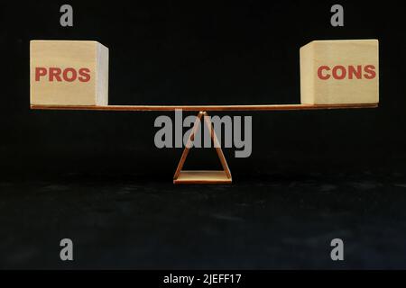 Equilibrio e pesare in e pro contro contro contro concetto. Pro e Cons parola in seesaw in nero scuro sfondo. Foto Stock