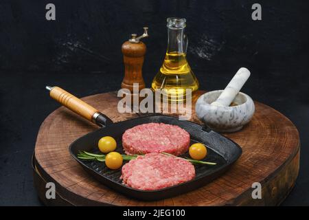 Cotoletta di hamburger di manzo crudo su una teglia in ghisa Foto Stock