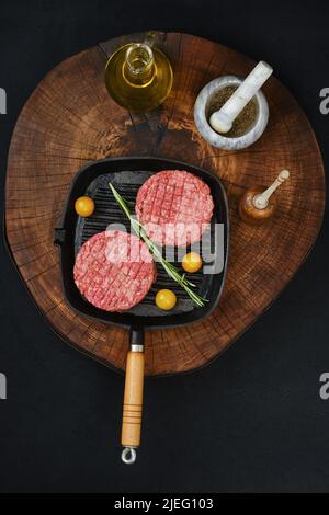 Vista dall'alto della cotoletta di hamburger di manzo crudo sulla teglia in ghisa Foto Stock