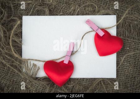 Biglietto d'auguri con foglio di carta vuoto e due cuori attaccati con clothespins ad una corda con spazio di copia Foto Stock