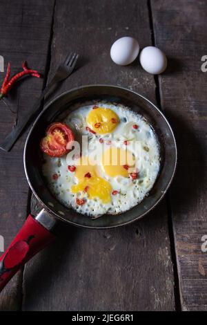 La colazione è servita con uova fritte in padella su sfondo. Vista dall'alto, messa a fuoco selettiva. Foto Stock