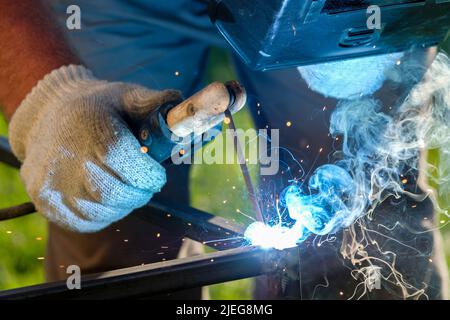 Scintille e fumo dalla saldatura metallica. Messa a fuoco selettiva. Saldatura di metalli mediante saldatura ad arco elettrica. Foto Stock
