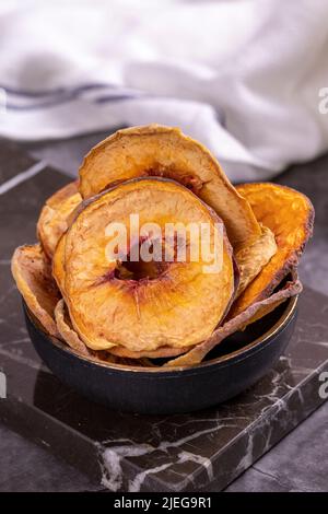 Fette di pesca essiccate. Pesche secche affettato su sfondo scuro. Frutta secca al sole. Primo piano. Foto Stock