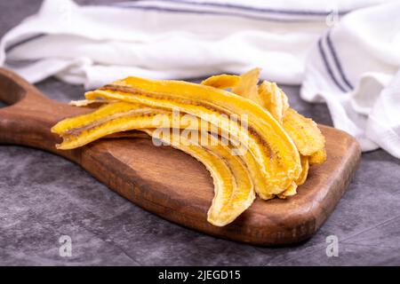 Fette di banana essiccate. Banana secca a fette su sfondo scuro. Frutta secca al sole. Primo piano Foto Stock