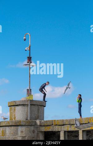 Giovani adolescenti che si arrampicano sul tetto di un rifugio sulla banchina di Newquay Harbour in Cornovaglia nel Regno Unito. Foto Stock