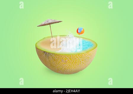 Spiaggia con onde di mare, ombrellone e palla su mezzo melone. Il concetto di rinfresco estivo con frutta e vitamine. Sfondo verde Foto Stock