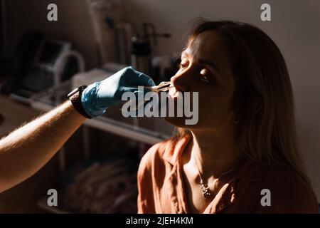 Rinoscopia del naso della donna. Consultazione con il medico. Otolaryngologist esamina il naso della ragazza prima della procedura di endoscopia del naso Foto Stock