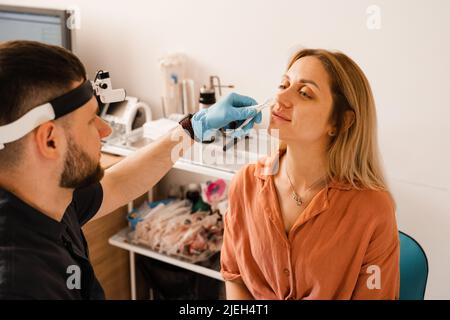 Rinoscopia del naso della donna. Consultazione con il medico. Otolaryngologist esamina il naso della ragazza prima della procedura di endoscopia del naso Foto Stock