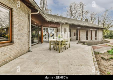 Patio lastricato pulito con area salotto e piccolo giardino vicino recinzione in legno Foto Stock