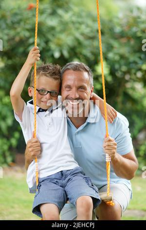 Vater mit Sohn im Garten , Sohn auf einer Schaukel, Sommer, Sohn, 4, Jahre, Mann, 45-50, Jahre Foto Stock