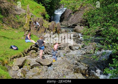 Una famiglia con due ragazzi che giocano nella cascata Ritson's Force a Wasdale in un giorno d'estate soleggiato Lake District Cumbria England UK Foto Stock