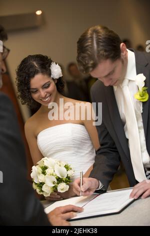 Verliebtes Brautpaar, 35, 40, Jahre, Mann, Frau, weisses Brautkleid, Anzugträger, Braut, Bräutigam, Unterschreibt auf dem Standesamt, Unterschrift, Foto Stock