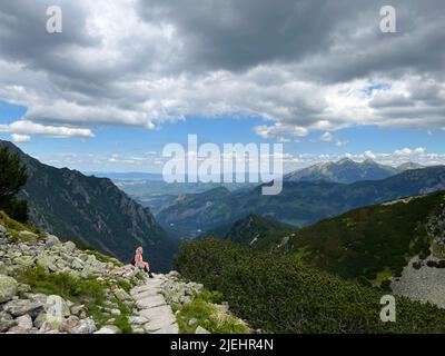 Vista panoramica delle montagne di Zakopane, Polonia, con una donna bionda che si rilassa su una collina sullo sfondo. Concetto di vita attiva. Escursioni nel mo Foto Stock