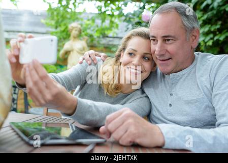 padre in pensione e figlia di mezza età che prende selfie Foto Stock