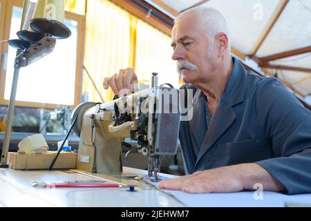 senior shoe o produttore di cinture nella sua officina di pelle Foto Stock