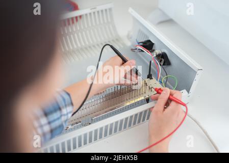 il multimetro esegue il test dell'elemento riscaldatore Foto Stock