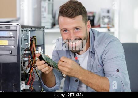 tecnico felice che lavora su un computer rotto Foto Stock
