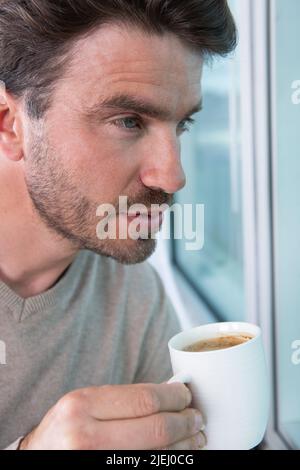 giovane uomo che beve caffè al mattino Foto Stock