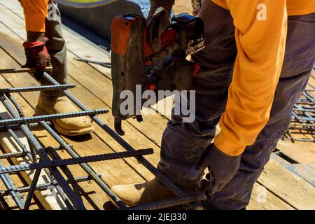 Attrezzo utilizzato dai lavoratori edili per legare le barre d'acciaio con le barre metalliche per fondazioni in cemento Foto Stock