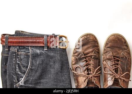 Scarpe in pelle marrone vintage e jeans neri elegantemente stressati isolati su sfondo bianco Foto Stock