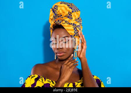 Ritratto di affascinante calma pelle scura donna braccia toccare testa viso isolato su sfondo blu Foto Stock