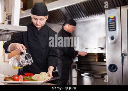 Cuoca femminile che lavora nella cucina del ristorante Foto Stock