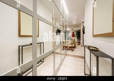 Stretto corridoio di una casa con un muro coperto di specchi incorniciati in piazze Foto Stock