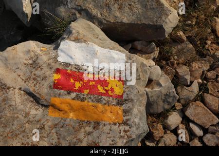 Bianco arancione e rosso linee dipinte su grandi rocce nella natura Foto Stock