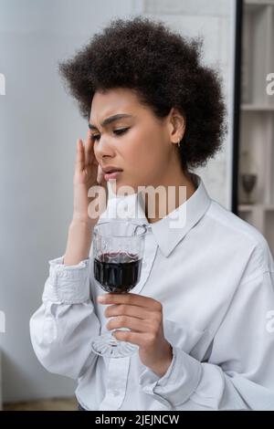 donna afro-americana frustrato che tiene un bicchiere di vino rosso Foto Stock