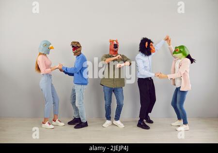 Gente divertente in maschere animali che ballano insieme Foto Stock