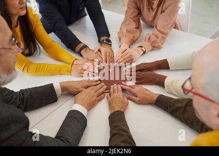 Gruppo multiculturale di persone che tengono le mani sulla Sacra Bibbia e pregano Foto Stock
