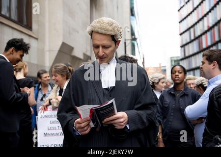 Londra, Regno Unito. 27th giugno 2022. Un barrister criminale è visto leggere un giornale fuori da Old Bailey. I barristi criminali scoppano dai tribunali in sciopero intorno al Regno Unito per disputa in pay. La Criminal Bar Association (CBA) ha dichiarato che i redditi per i barristi criminali junior sono scesi del 30% negli ultimi 20 anni e che hanno raggiunto un reddito medio dopo le spese di £12200 nei primi 3 anni di pratica. Essi richiedono un aumento del 25% della tassa di assistenza legale, che è superiore al 15% minimo raccomandato dalla revisione penale di assistenza legale pubblicata lo scorso dicembre. Credit: SOPA Images Limited/Alamy Live News Foto Stock