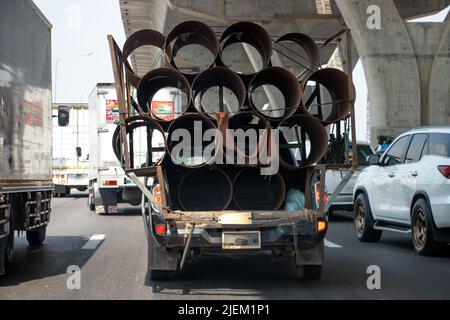 Un pick-up a pieno carico trasporta tubi in acciaio sull'autostrada Foto Stock