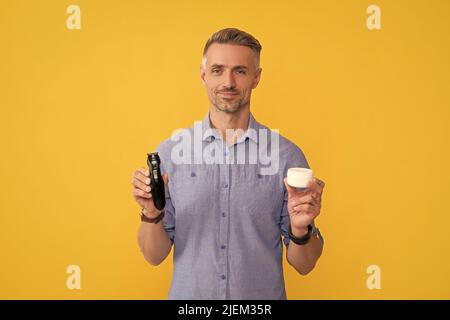 bellezza uomo. barbiere. dopo la rasatura. uomo che tiene rasoio elettrico e crema. Foto Stock