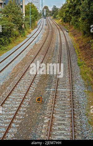 Vista di tre vecchie linee ferroviarie che conducono da una città in Danimarca. Viaggia e viaggia con il treno pubblico per lavorare. Acciai abbandonati rotaie per il trasporto merci Foto Stock