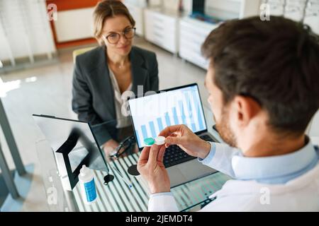 Optometristo maschio che dà la coppia di lenti a contatto nel caso al paziente che offre la scelta Foto Stock