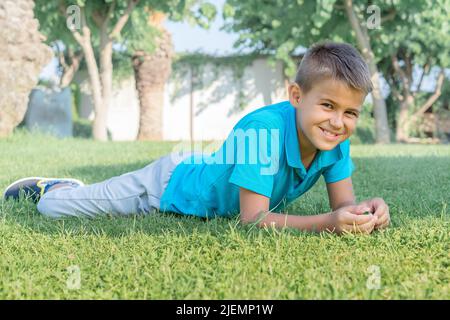 Il ragazzo allegro si trova sull'erba del parco. Foto Stock