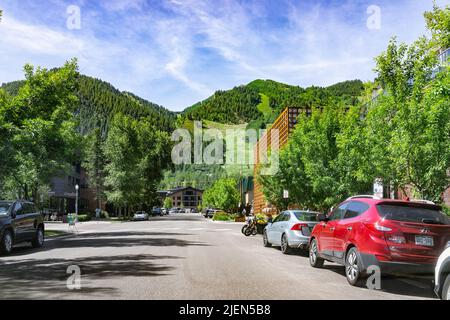 Aspen, USA - 18 luglio 2019: Piccola città in Colorado con vista di piste da sci in una lussureggiante estate verde dalla strada in città costosa con auto parcheggiate par Foto Stock