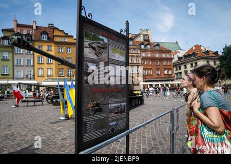 Le donne leggono informazioni sulle distrutte attrezzature militari russe nel centro di Varsavia. La mostra di attrezzature russe distrutte durante la guerra in Ucraina si è aperta alla Piazza del Castello nel centro di Varsavia. Varsavia è diventata la prima capitale europea ad invitare la mostra organizzata dalla Cancelleria del primo Ministro dalla parte polacca e dal Ministero della difesa dell'Ucraina dalla parte Ucraina. I visitatori possono vedere il serbatoio T-72-B e il sistema di artiglieria semovente Howitzer 2S19 Msta-S, nonché campioni di conchiglie. Foto Stock