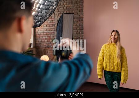 Giovane fotografo che prende le foto di modello, backstage di fotografare in studio. Foto Stock