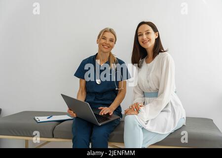 Il terapista conduce un esame preventivo di una donna nel suo ufficio e guardando la macchina fotografica Foto Stock